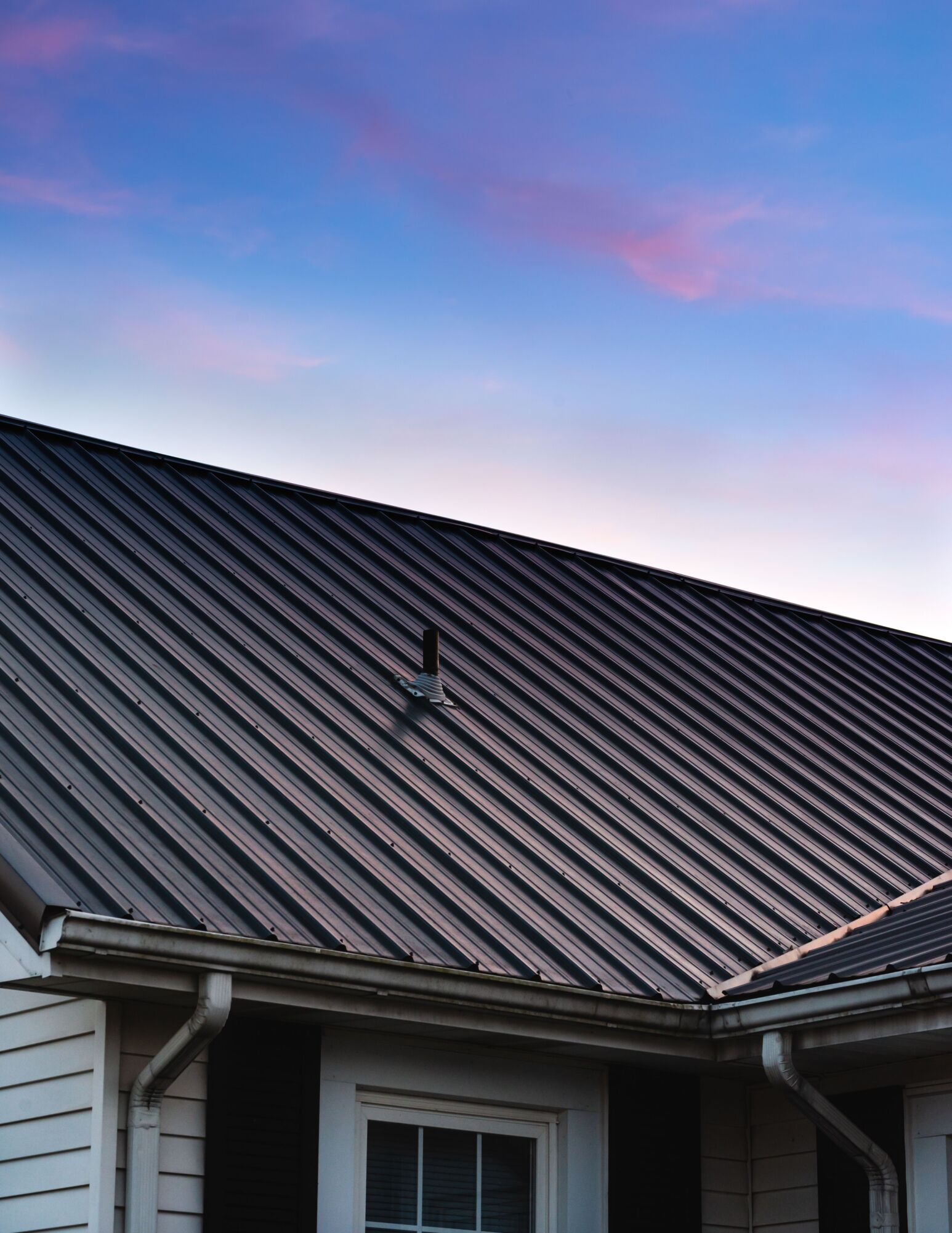 Metal roof under colorful sunset sky.